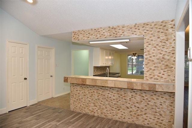 13407 Linden St, Sugar Land, TX 77498 - kitchen with wood finished floors, white cabinets, a sink, a textured ceiling, and baseboards