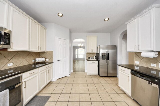 11311 Burmese Ln, Sugar Land, TX 77478 - kitchen with appliances with stainless steel finishes, arched walkways, tasteful backsplash, dark countertops, and recessed lighting