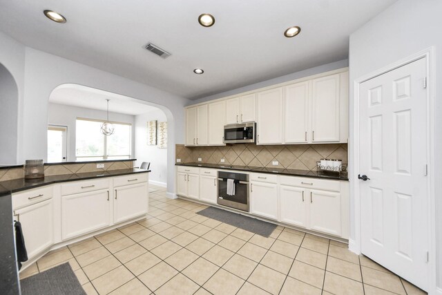 11311 Burmese Ln, Sugar Land, TX 77478 - kitchen featuring appliances with stainless steel finishes, arched walkways, dark countertops, backsplash, and recessed lighting