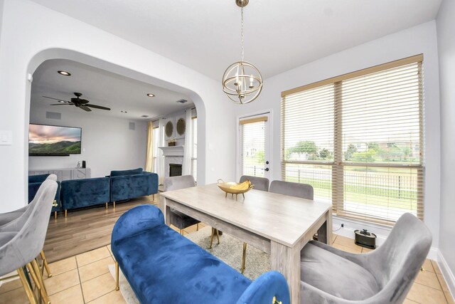 11311 Burmese Ln, Sugar Land, TX 77478 - dining room featuring arched walkways, light tile patterned floors, a fireplace, a chandelier, and baseboards