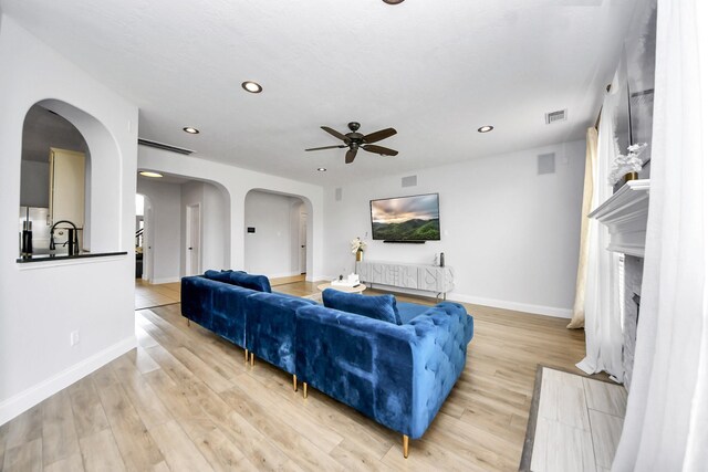 11311 Burmese Ln, Sugar Land, TX 77478 - living area with arched walkways, ceiling fan, recessed lighting, a fireplace, and light wood-style floors