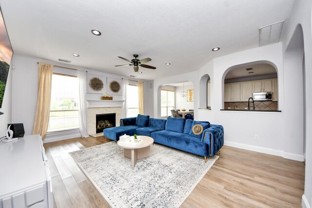 11311 Burmese Ln, Sugar Land, TX 77478 - living area with light wood-style flooring, ceiling fan, arched walkways, recessed lighting, and a fireplace with raised hearth