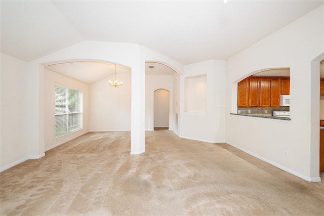 3226 Woodwind Rd, Montgomery, TX 77356 - unfurnished living room featuring arched walkways, a chandelier, light carpet, and vaulted ceiling