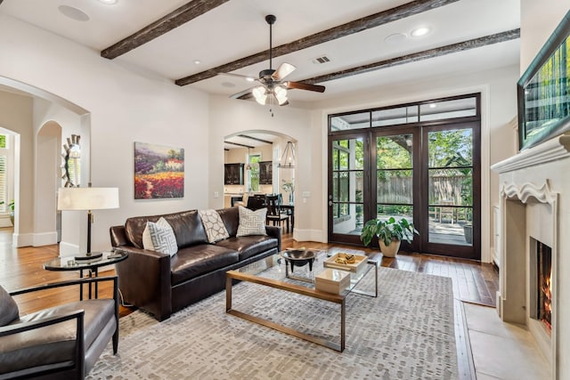 6014 Floyd St, Houston, TX 77007 - living room featuring arched walkways, a fireplace with flush hearth, light wood-type flooring, ceiling fan, and beam ceiling