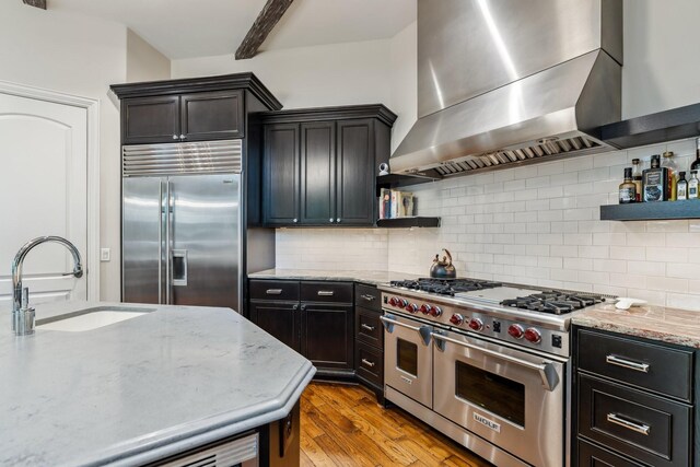 6014 Floyd St, Houston, TX 77007 - kitchen with high end appliances, wall chimney range hood, open shelves, wood finished floors, and decorative backsplash