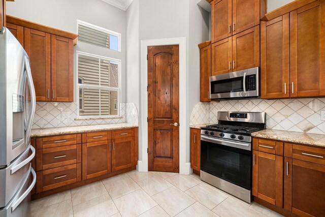 2022 Sabine St, Houston, TX 77007 - kitchen featuring appliances with stainless steel finishes, ornamental molding, decorative backsplash, light stone countertops, and brown cabinetry