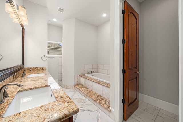 2022 Sabine St, Houston, TX 77007 - full bathroom featuring marble look tiles, a garden tub, double vanity, baseboards, and recessed lighting