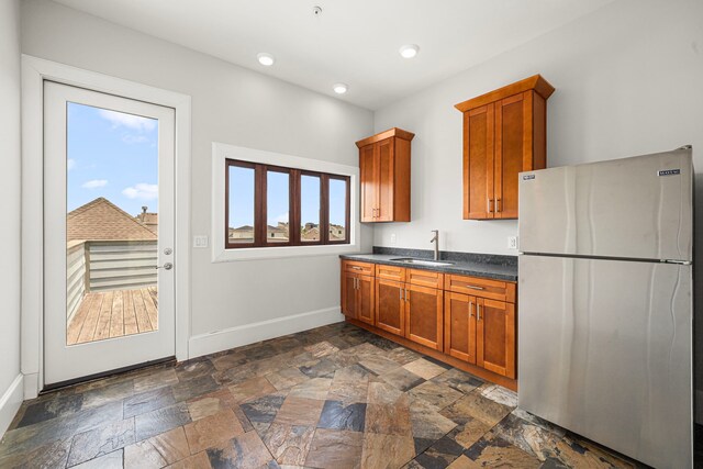 2022 Sabine St, Houston, TX 77007 - kitchen featuring freestanding refrigerator, dark countertops, baseboards, a sink, and brown cabinetry