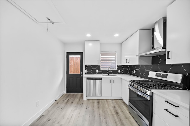 1106 W Tri Oaks Ln Unit 134, Houston, TX 77043 - kitchen with appliances with stainless steel finishes, wall chimney exhaust hood, light countertops, light wood-type flooring, and white cabinets