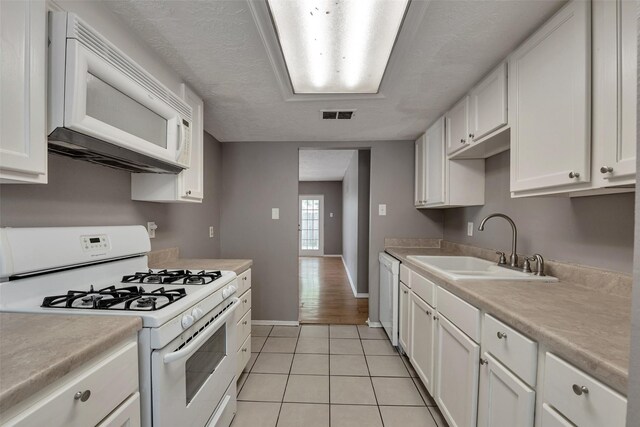 20110 Misty Pines Dr, Humble, TX 77346 - kitchen with white appliances, a sink, white cabinets, light countertops, and light tile patterned flooring