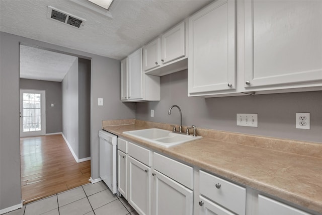 20110 Misty Pines Dr, Humble, TX 77346 - kitchen featuring white dishwasher, a sink, white cabinets, light tile patterned floors, and a textured ceiling