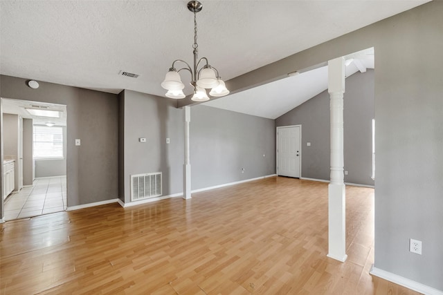 20110 Misty Pines Dr, Humble, TX 77346 - spare room featuring light wood finished floors, a chandelier, baseboards, vaulted ceiling, and a textured ceiling