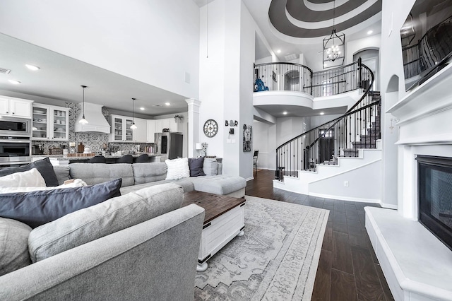 23230 Banfield Creek Ct, Katy, TX 77493 - living area featuring dark wood finished floors, a glass covered fireplace, a towering ceiling, recessed lighting, and baseboards