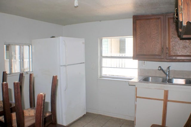 1611 Chapman St, Houston, TX 77009 - kitchen featuring a sink, light tile patterned floors, light countertops, brown cabinets, and freestanding refrigerator