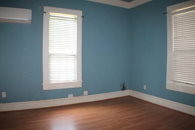 1611 Chapman St, Houston, TX 77009 - spare room with an AC wall unit, wood finished floors, and baseboards