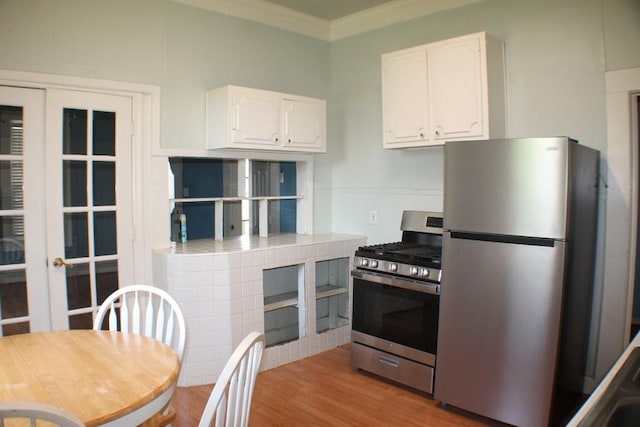 1611 Chapman St, Houston, TX 77009 - kitchen featuring appliances with stainless steel finishes, white cabinets, crown molding, wood finished floors, and french doors