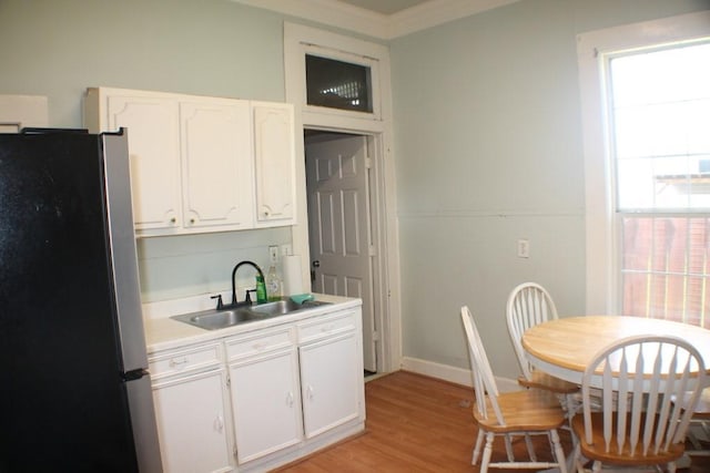 1611 Chapman St, Houston, TX 77009 - kitchen with freestanding refrigerator, a sink, white cabinets, light wood-style floors, and light countertops