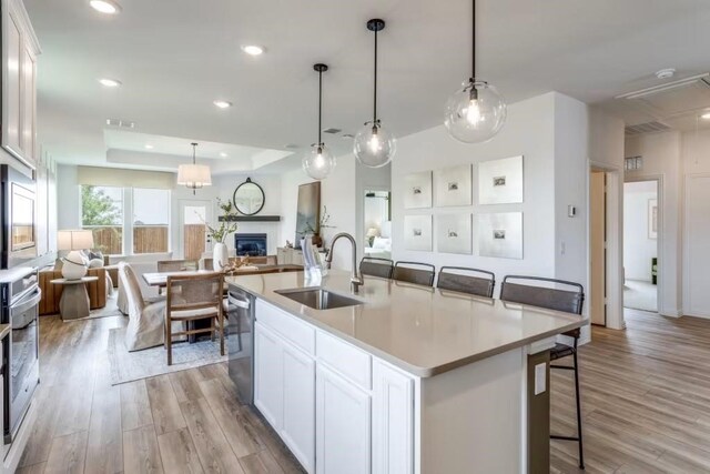 5238 Oakland Bluff Ln, Richmond, TX 77469 - kitchen with a sink, open floor plan, stainless steel appliances, light wood-style flooring, and white cabinets