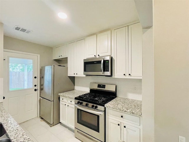 16303 Napa Vine Dr, Houston, TX 77053 - kitchen featuring stainless steel appliances, decorative backsplash, white cabinets, light stone countertops, and light tile patterned floors