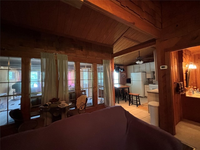 11 Sherry Ln, Coldspring, TX 77331 - bedroom featuring freestanding refrigerator, wood ceiling with exposed beams, multiple windows, wood walls, and light tile patterned floors