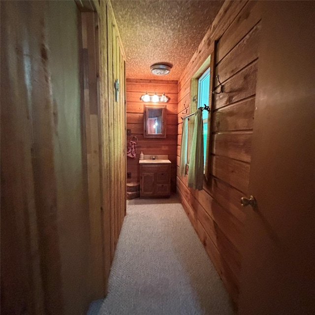 11 Sherry Ln, Coldspring, TX 77331 - hallway featuring wood walls, a textured ceiling, and light colored carpet