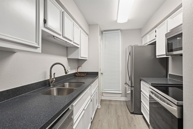 215 Post Office St Unit 1208, Galveston, TX 77550 - kitchen featuring stainless steel appliances, a sink, light wood finished floors, white cabinets, and baseboards