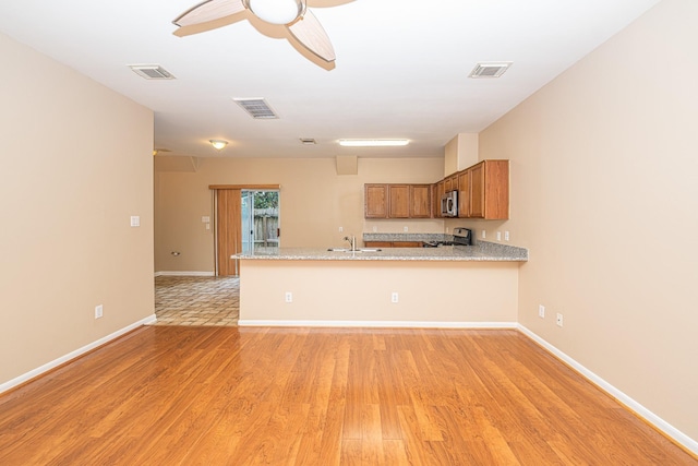 2212 Naomi St, Houston, TX 77054 - kitchen featuring stove, stainless steel microwave, a peninsula, brown cabinets, and light wood-style floors
