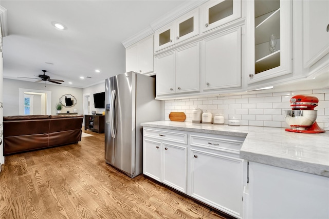 423 Pecore St, Houston, TX 77009 - kitchen with stainless steel fridge, white cabinetry, ceiling fan, light wood-style flooring, and decorative backsplash
