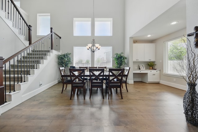 3601 Haskell Hollow Loop, College Station, TX 77845 - dining area with a towering ceiling, wood finished floors, a chandelier, stairs, and baseboards