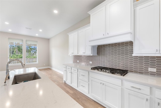24815 Pavonia Lake Ln, Tomball, TX 77375 - kitchen featuring stainless steel gas cooktop, backsplash, white cabinetry, recessed lighting, and light wood-style flooring