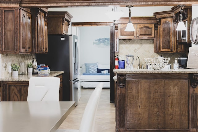 4023 Avenue S, Galveston, TX 77550 - kitchen featuring decorative backsplash, pendant lighting, dark brown cabinetry, and light stone counters