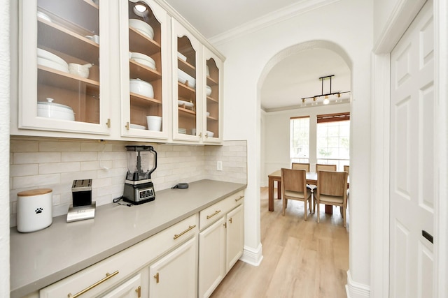 527 Little River Ct, Richmond, TX 77406 - kitchen featuring crown molding, arched walkways, backsplash, light wood-style flooring, and light countertops
