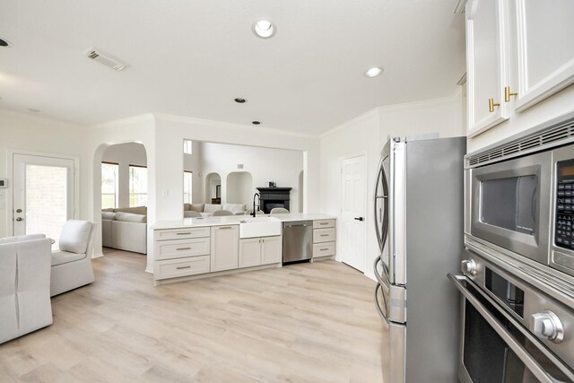 527 Little River Ct, Richmond, TX 77406 - kitchen with stainless steel appliances, open floor plan, a sink, arched walkways, and light wood-type flooring