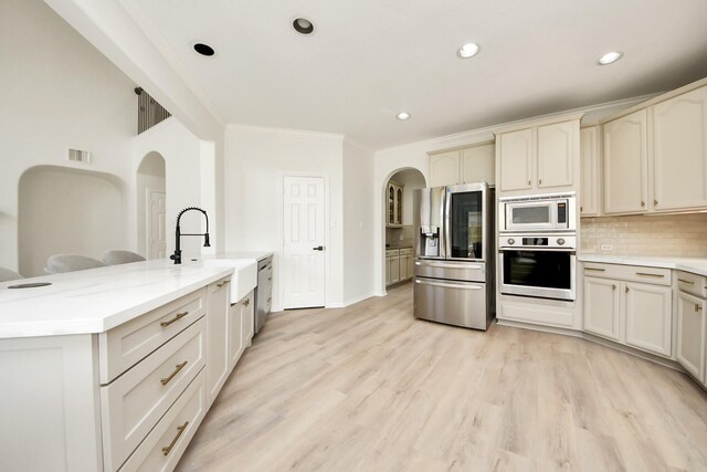 527 Little River Ct, Richmond, TX 77406 - kitchen featuring appliances with stainless steel finishes, a sink, arched walkways, tasteful backsplash, and recessed lighting