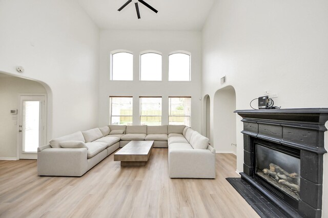 527 Little River Ct, Richmond, TX 77406 - living area with arched walkways, a glass covered fireplace, a towering ceiling, a ceiling fan, and wood finished floors