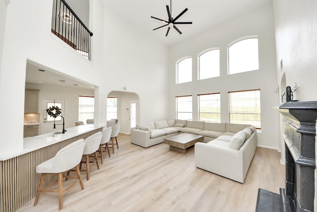 527 Little River Ct, Richmond, TX 77406 - living room with arched walkways, a ceiling fan, a towering ceiling, wood finished floors, and plenty of natural light