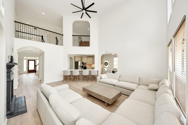 527 Little River Ct, Richmond, TX 77406 - living room with arched walkways, a towering ceiling, a ceiling fan, light wood-style flooring, and baseboards