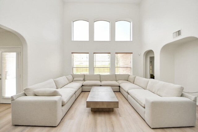 527 Little River Ct, Richmond, TX 77406 - living area with arched walkways, a high ceiling, light wood-type flooring, and healthy amount of natural light
