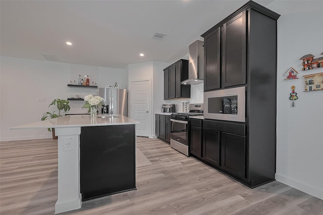12319 Brandenburg Gate Dr, Houston, TX 77047 - kitchen with stainless steel appliances, wall chimney range hood, light wood-style floors, light countertops, and an island with sink