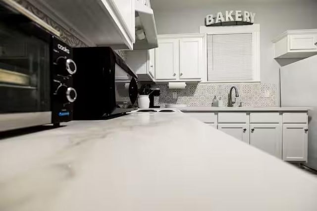 1514 18th St, Galveston, TX 77550 - kitchen featuring tasteful backsplash, white cabinetry, light countertops, and a sink