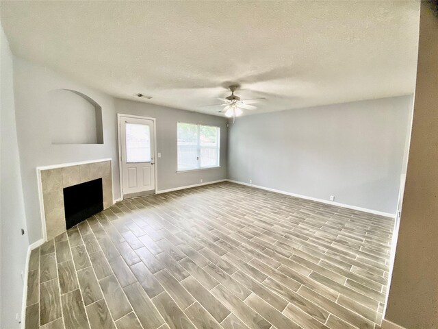 17419 Prospect Meadows Dr, Houston, TX 77095 - unfurnished living room with ceiling fan, baseboards, wood finished floors, a textured ceiling, and a tiled fireplace