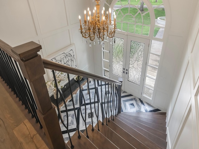 23226 Oak Hollow Ln, Tomball, TX 77377 - stairway featuring a decorative wall, a chandelier, plenty of natural light, french doors, and wood finished floors