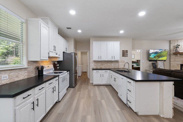 11402 Willis Waukegan Rd, Conroe, TX 77303 - kitchen with white appliances, a sink, dark countertops, a peninsula, and recessed lighting
