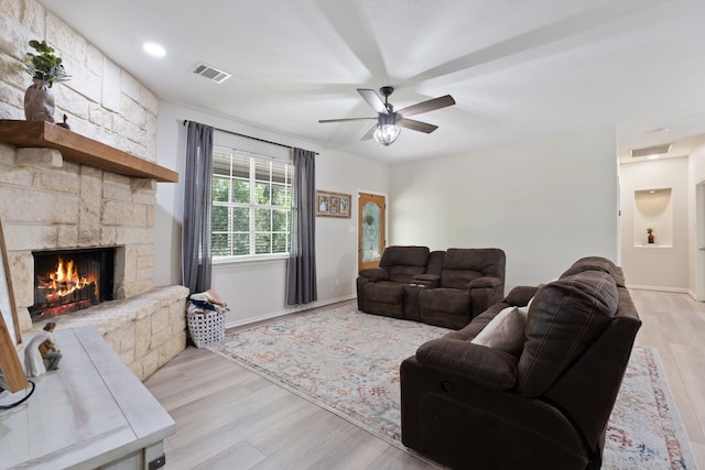 11402 Willis Waukegan Rd, Conroe, TX 77303 - living room featuring light wood-type flooring, ceiling fan, a stone fireplace, and baseboards