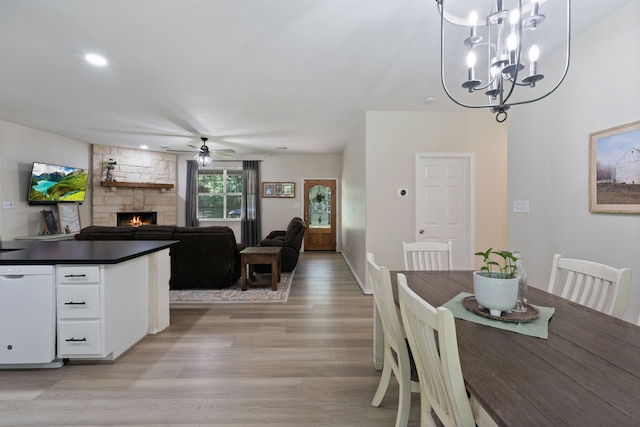 11402 Willis Waukegan Rd, Conroe, TX 77303 - dining space with ceiling fan, light wood-style floors, a stone fireplace, a chandelier, and baseboards