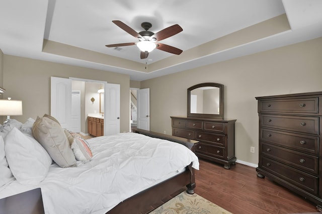 20530 Saddleback Chase Ln, Cypress, TX 77433 - bedroom featuring a tray ceiling, dark wood-style flooring, baseboards, ensuite bathroom, and a ceiling fan