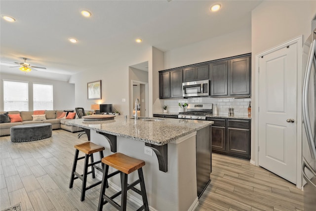 21231 Flowering Crape Myrtle Dr, Porter, TX 77365 - kitchen with appliances with stainless steel finishes, a sink, a ceiling fan, a kitchen breakfast bar, and backsplash