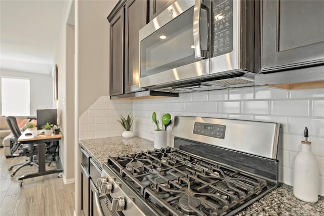 21231 Flowering Crape Myrtle Dr, Porter, TX 77365 - kitchen featuring appliances with stainless steel finishes, dark brown cabinets, light stone countertops, decorative backsplash, and light wood-type flooring