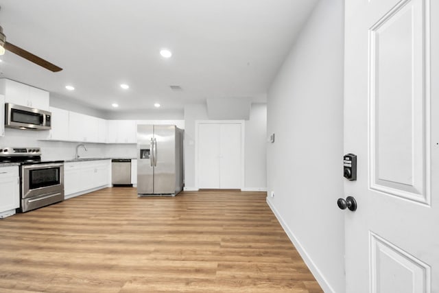 6617 Bacher St, Houston, TX 77028 - kitchen featuring stainless steel appliances, recessed lighting, light wood-type flooring, white cabinets, and a sink