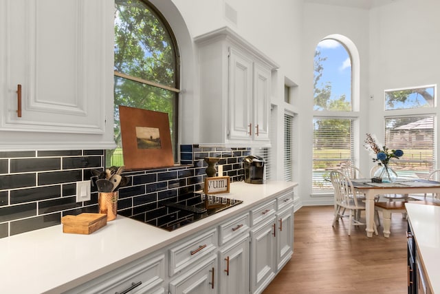 2623 Old S Dr, Richmond, TX 77406 - kitchen with a high ceiling, white cabinets, black electric cooktop, tasteful backsplash, and light countertops